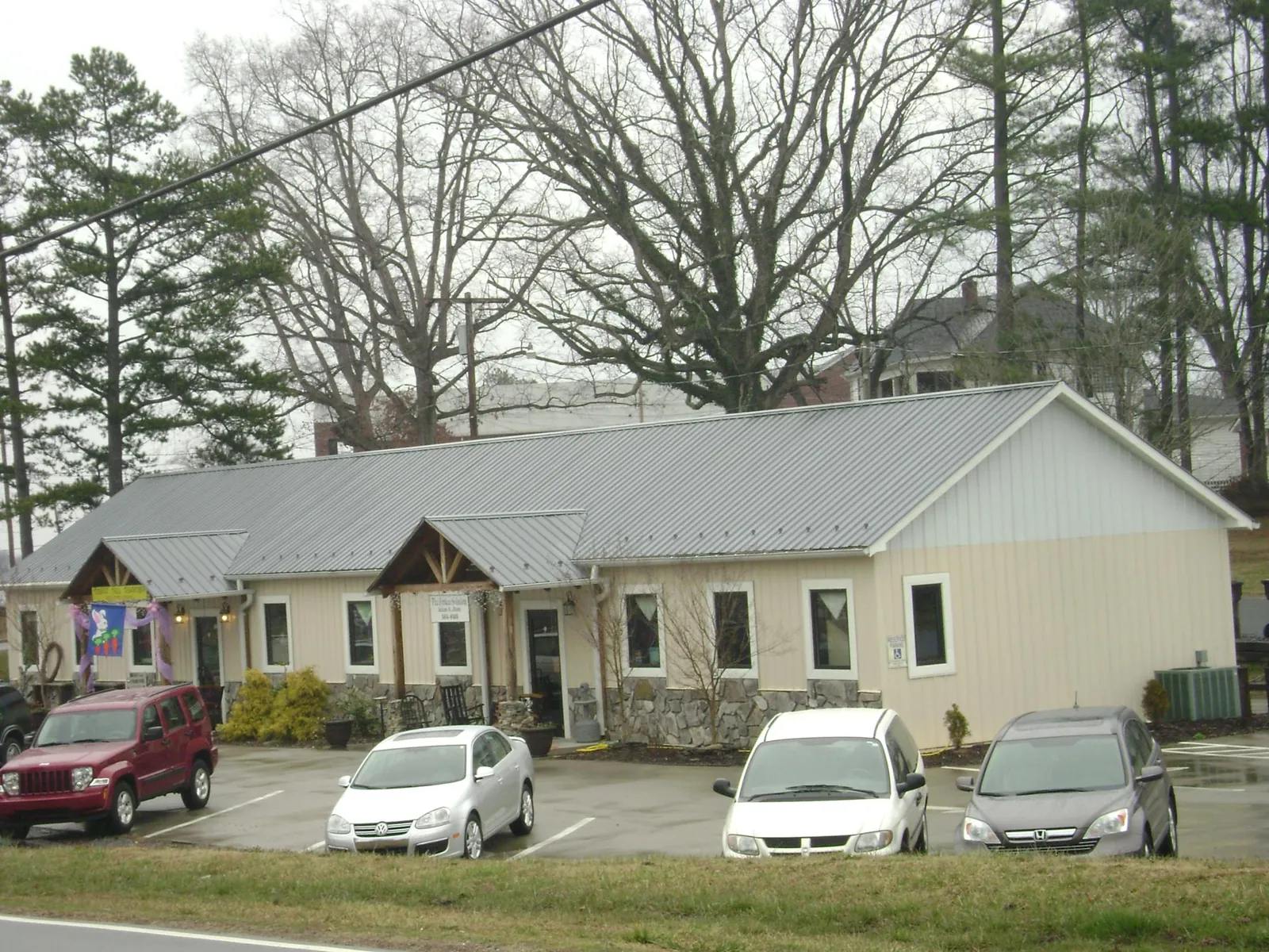Gray metal roof with timber entry brackets on a small commercial building in Rogers